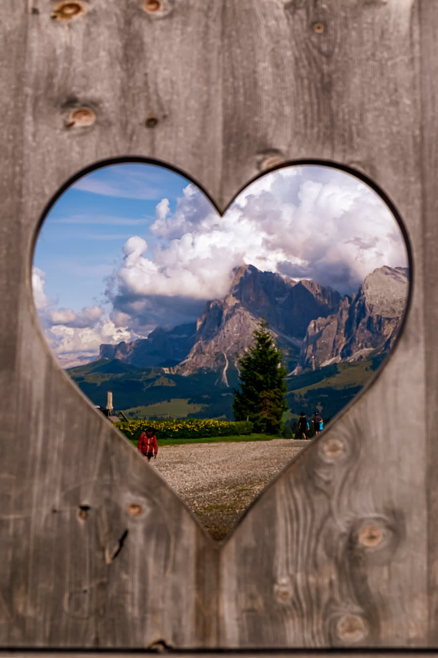 A mountain framed through a heart cut into a wooden panel