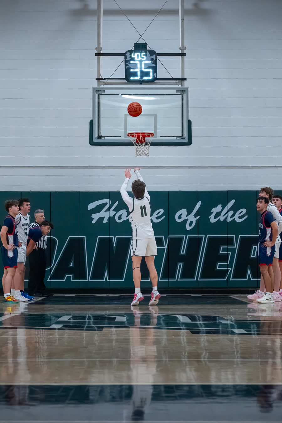A jump shot at the top of its arc under the shot clock
